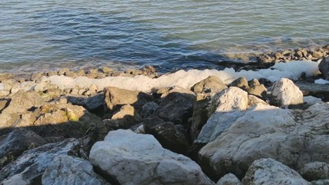 Dangerous sea foam on the rocky shoreline -wide