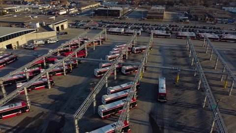 TTC public transit buses at large operations, maintenance and storage facility as multiple buses drive through parking lot; aerial