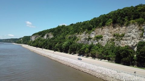 Beautiful 4K drone footage of a highway along cliffside and lake on a summer day.