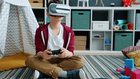 Boy wearing virtual reality glasses is playing video game using controller and looking around having fun alone. Childhood and entertainment concept.