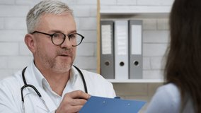 Male Doctor Talking With Sick Female Patient In Clinic