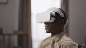 young black man is enjoying virtual reality, viewing 3d video by head-mounted display, vr glasses for entertainment and education, male portrait at home
