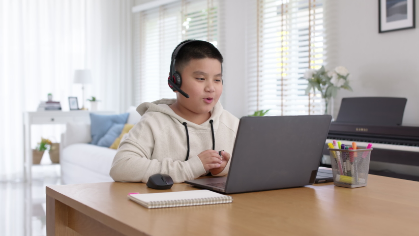 Young asia boy student wear headset headphone with computer laptop videocall talk present online e-learning class study with teacher, social distance learn language at home, homeschooling concept. | Shutterstock HD Video #1069386889