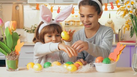 Happy family Easter. Funny kids play game with painted eggs at home. Funny kids play Easter hare hunters, knock spoons on eggs