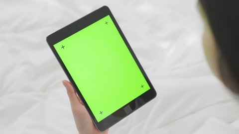 Close up of woman holding in hands a digital tablet with green screen for internet online, chroma key screen for advertising.