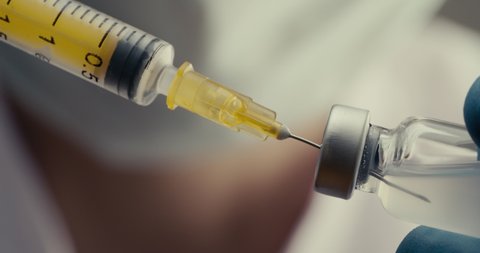 Doctor filling syringe with vaccine