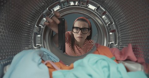 Shocked woman finds her smartphone in the washing machine after doing laundry, point of view shot