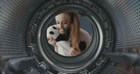 Woman washing a cute panda plush in the washing machine, point of view shot