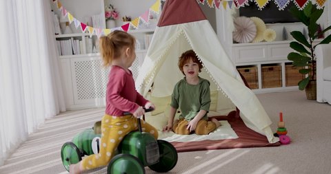 cute happy siblings playing together in nursery room, cozy home interior