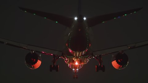 Jet air plane comes in to land. Night time. Transportation, flights and travel concepts. Bad weather, grounded aircraft fleet, covid pandemic. Airlines closing down. Dark ominous feeling. 4k footage.
