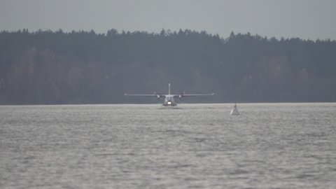 The Twin-engine seaplane, seaplane rises from water at the forest lake, northern land. Utility seaplane. Slow motion