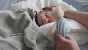 father playing with newborn baby, baby boy lying in baby pod nest, father's hand holds a soft toy. High quality 4k footage