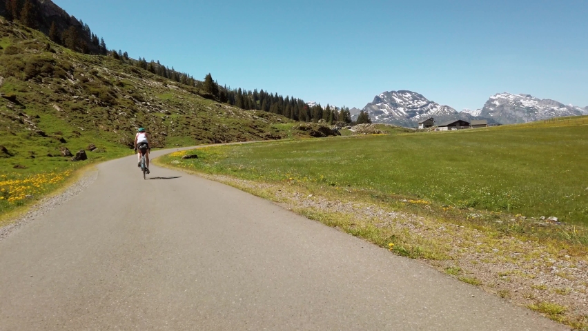 Following closely behind a bicyclist as they wind through a picturesque Pragel Pass, Switzerland