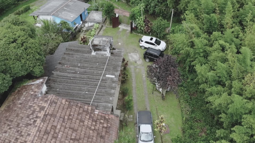 Aerial view of a house and cars in the middle of the jungle