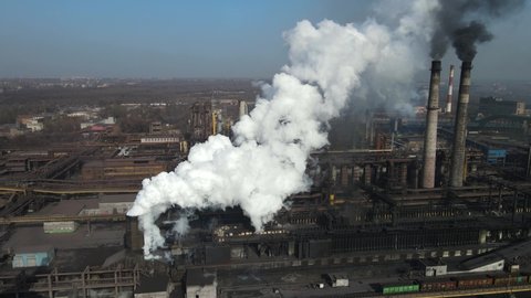 Aerial footage of the pipes of a steel plant taken from drones. high above the metallurgical plant and a cloud of smoke is coming from the chimney.