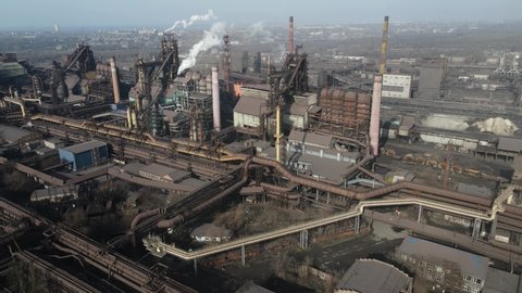 Aerial footage of the pipes of a steel plant taken from drones. high above the metallurgical plant and a cloud of smoke is coming from the chimney.