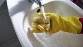 A girl in rubber gloves does the cleaning in the bathroom and washes a bidet.