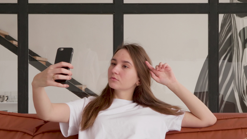 young beautiful white blond woman takes selfies on her phone at home