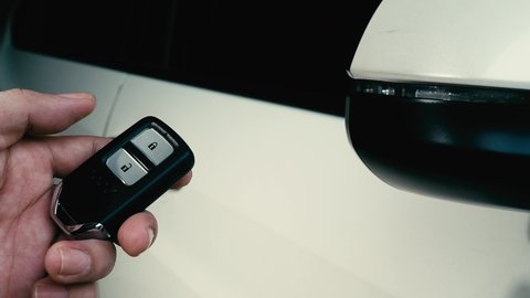 Car key remote control. Locking and unlocking the car by the car key remote control. Pressing the button of the car key and the lights  blink when door open or closed. Man hand using remote key.