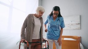 aged woman stepping with walkers near geriatric nurse