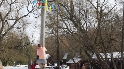 climbing dudes on pillar during Maslenitsa celebration in Dudutki.Minsk.Belarus - March 10 2021