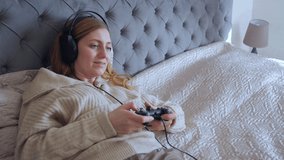 Woman lying and playing video games with gamepad on bed