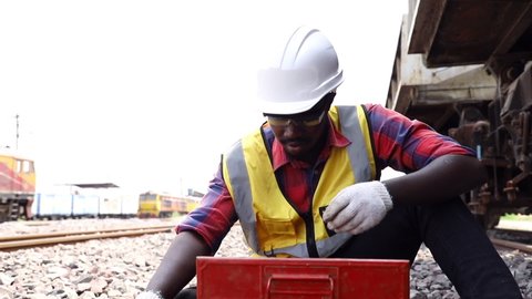 Handsome Africa American industrial engineering maintenance prepare and holding tool for fix railway at garage plants with wrench. Engineer and repair man concept. Safety first