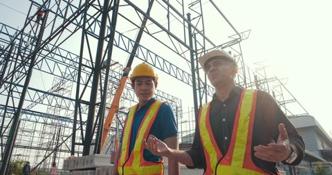 Two diversity engineers Caucasian and Asian man discuss plan of building at construction site, Real estate project with civil engineer. Arkivvideo