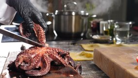 Chef cutting boiled octopus with knife. Boiling saucepan and utensil in background. Healthy food and vegetarian concept. Seafood restaurant. Gourmet 4 k video