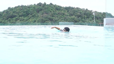 person swimming in the pool, Smart middle-aged women swim goggles swimming in blue pool. Active Asian Senior enjoying exercise relaxing in sport pool when stay Travel vacation at hotel in Phuket
