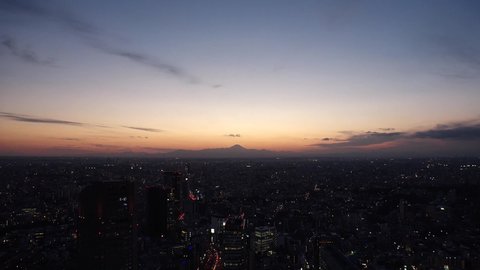 TOKYO, JAPAN : Aerial sunrise CITYSCAPE of TOKYO and MOUNT FUJI. View of rising sun and buildings around Shibuya. Japanese city life and nature concept. Time lapse zoom in video, night to morning.