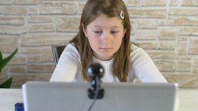 Young girl follows school lessons connected to pc at home 
