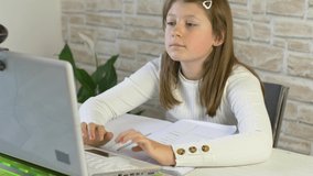 Young girl follows school lessons connected to pc at home 