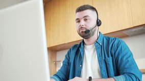 Bearded casual young man in headset speaking webcam looking at laptop make notes male sales representative talking by video call study online consulting customer selling service support working home