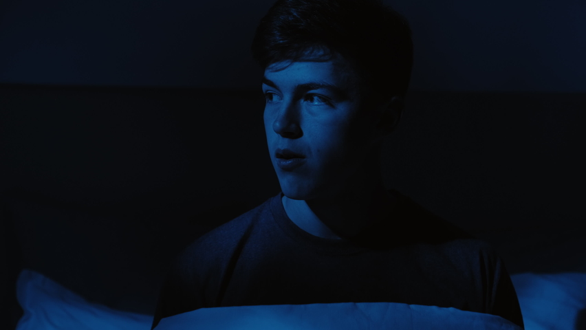 Nightmare fear. Scary dream. Panic attack. Disturbed frightened shocked guy raised up in bed fell asleep late at home in dark blue light. | Shutterstock HD Video #1069457839