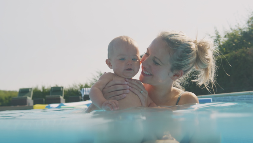Mother with baby daughter playing and having fun on summer vacation in outdoor swimming pool - shot in slow motion | Shutterstock HD Video #1069462138