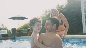 Father with young son playing and having fun on summer vacation in outdoor swimming pool as mother sits on edge - shot in slow motion - Powered by Shutterstock - Get 15% off with code: PIKWIZARD15