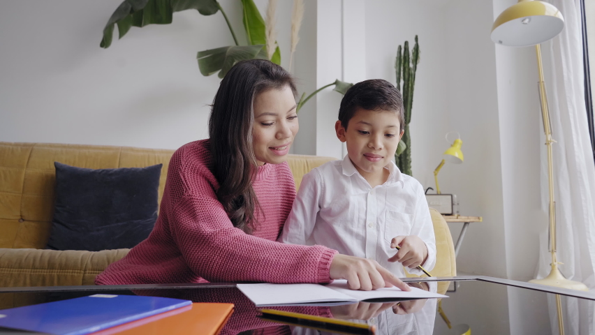 Mother helping her son with his homework in the living room at home. Royalty-Free Stock Footage #1069463002