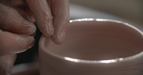 Close up view: potter sculpts a ceramic jug on a potter's wheel, the potter makes even edge of a clay jar, making of ceramics in slow motion, 4k 60p Prores HQ 10 bit