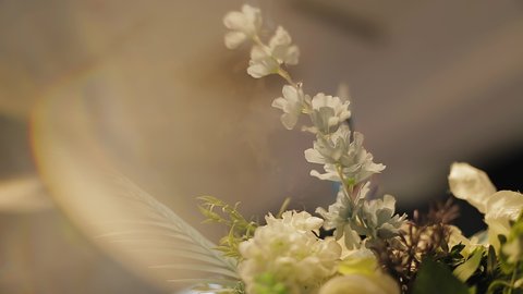 A beautiful detail of the decor of fresh flowers in the room at the event. The camera moves smoothly with a tilt