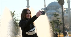 the traveler takes a selfie, against the backdrop of fountains, and a mosque, Sheikh Zayed Grand Mosque. tourist walks around historical sites in Abu Dhabi, slow motion european girl in arab country 