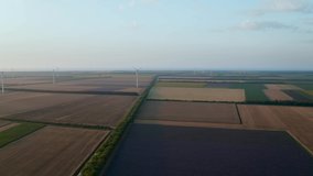 Aerial fly above wind turbines across summer agricultural field. Clean and renewable wind power farm in motion. Green energy, sustainable alternative electricity, no pollution environment.