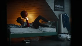WIDE Bored African American Black kid teenager boy playing with basketball in his attic bedroom at home. Shot with 2x anamorphic lens - Powered by Shutterstock - Get 15% off with code: PIKWIZARD15