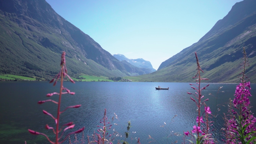 Rowboat On Beautiful Mountain Lake with flowers in the foreground on a sunny day, scenic norwegian ladscape.