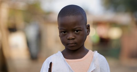 Poverty.Inequality.Portrait of a poor Black African boy looking at camera with a sad expression in a slum surrounding