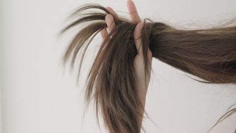 Close up woman holding hair with dry damaged hair problem on white background. Woman upset with dry damaged hair.