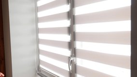 Overexposed video. Woman opening blinds or curtains on the window. Sunny day. Solar light through closed blinds. Sunshine and warm at home.