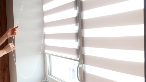 Overexposed video. Woman opening blinds or curtains on the window. Sunny day. Solar light through closed blinds. Sunshine and warm at home.