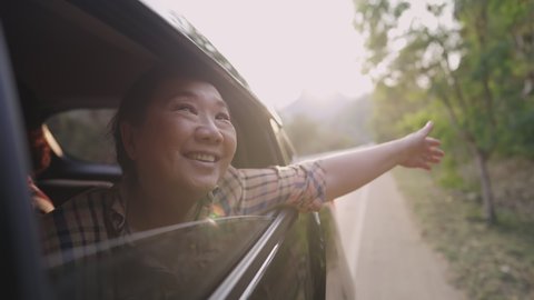 Cheerful senior enjoying good feeling through country road, elderly woman extended her head out of moving auto with her long hair dropped outside of window's car, happiness of retirement