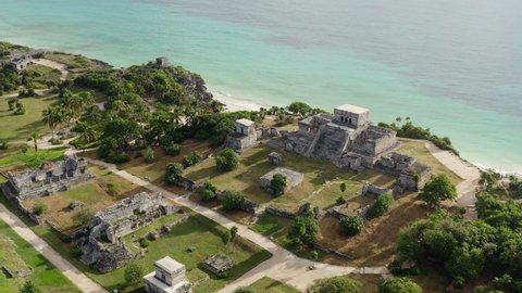 Drone video of the Mayan pyramids. Ancient buildings with temples stand on a rock by the sea in a beautiful landscape in the historic city of Tulum. Aerial view Cancun Mexico.